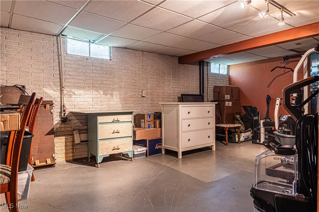 Basement with a paneled ceiling and brick wall