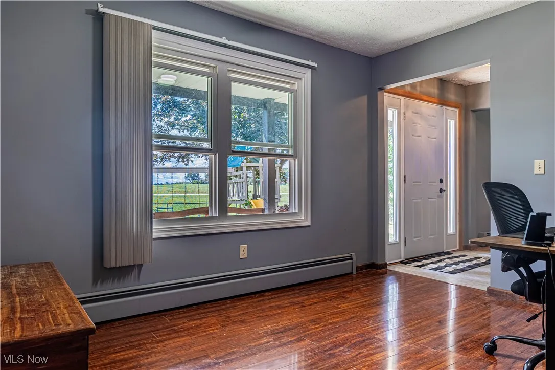 Office with baseboard heating, a textured ceiling, and dark wood-style flooring
