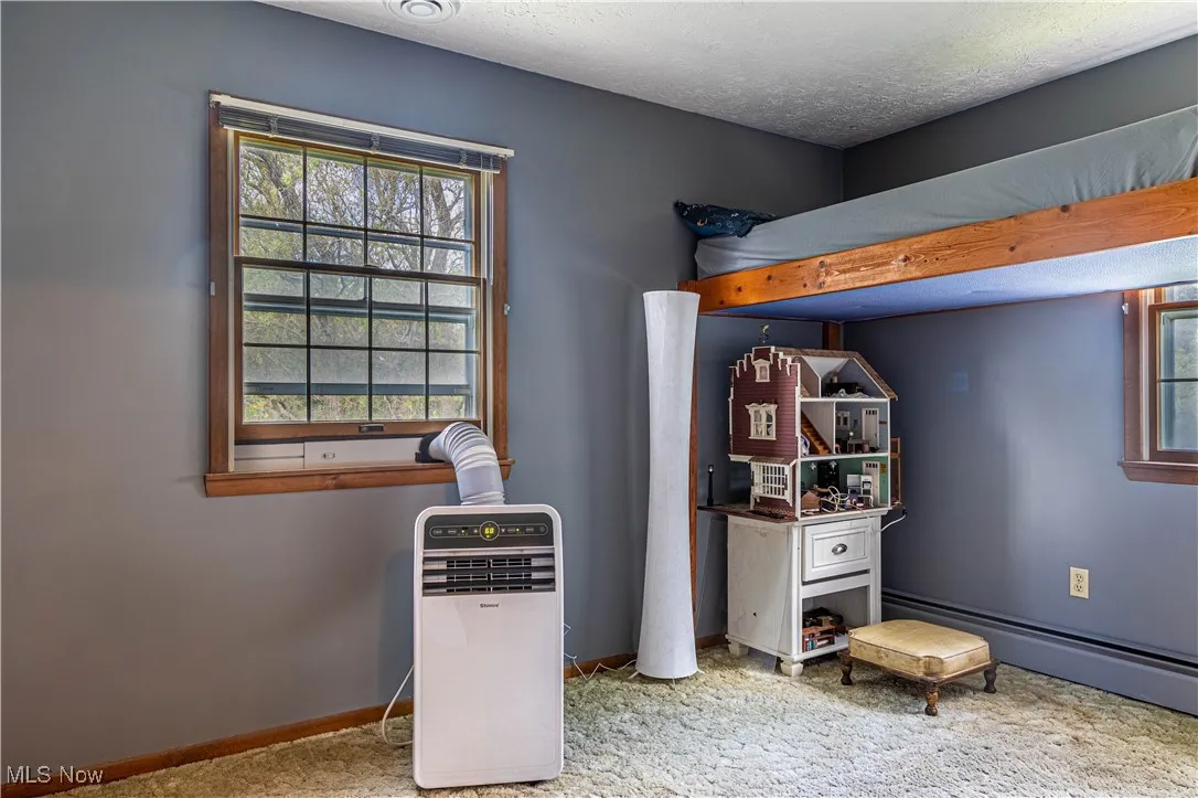 Bedroom with a textured ceiling and baseboard heating