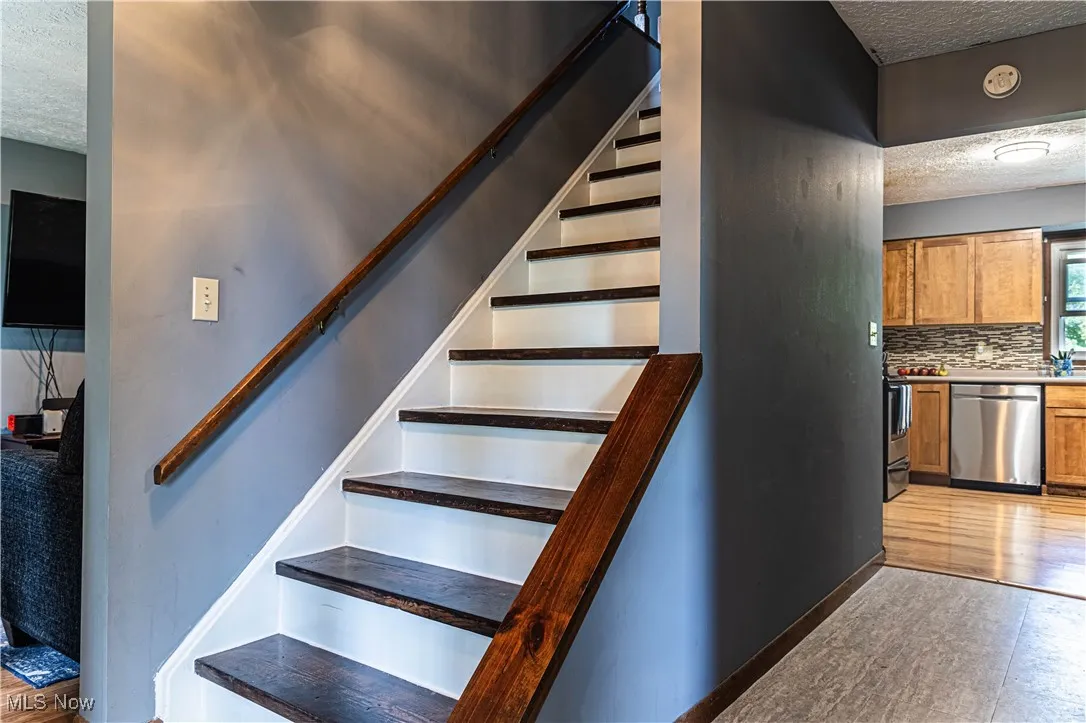 Stairs with a textured ceiling and wood finished floors