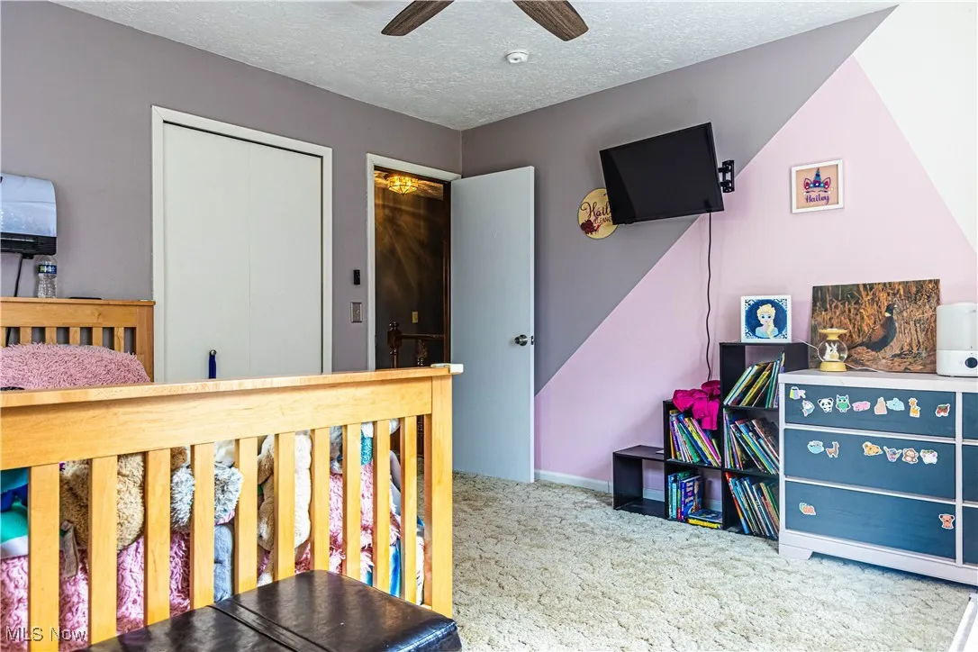 Bedroom with a textured ceiling, light carpet, and ceiling fan