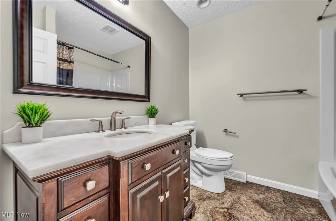 Full bath featuring a textured ceiling and vanity
