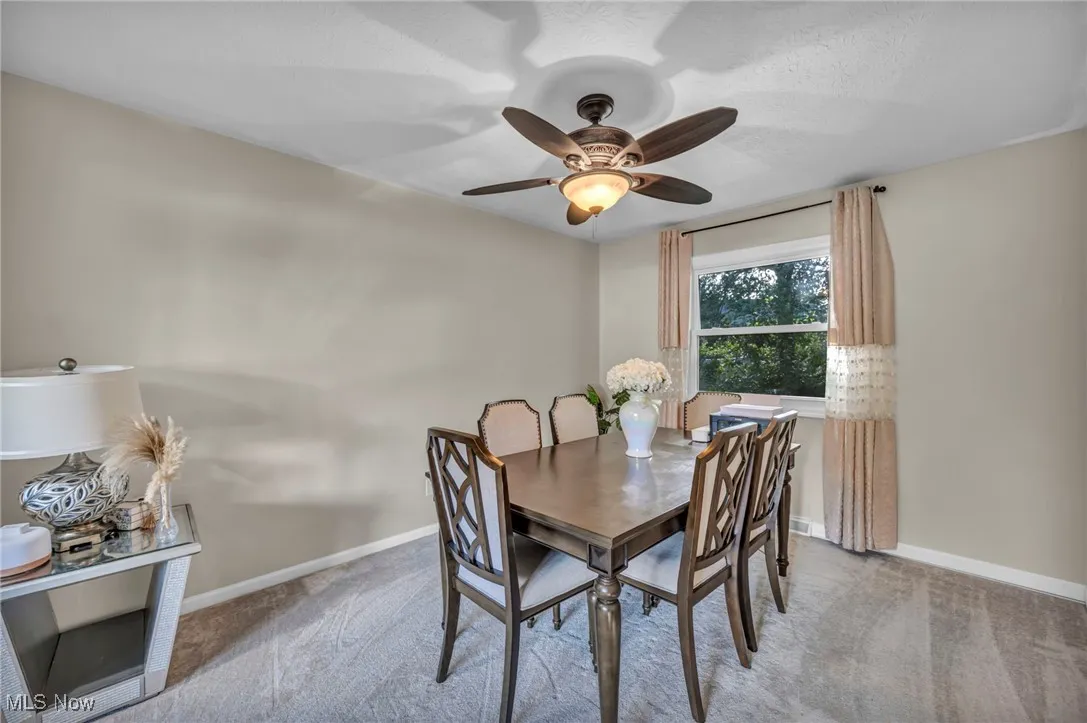 Dining area with light carpet and a ceiling fan