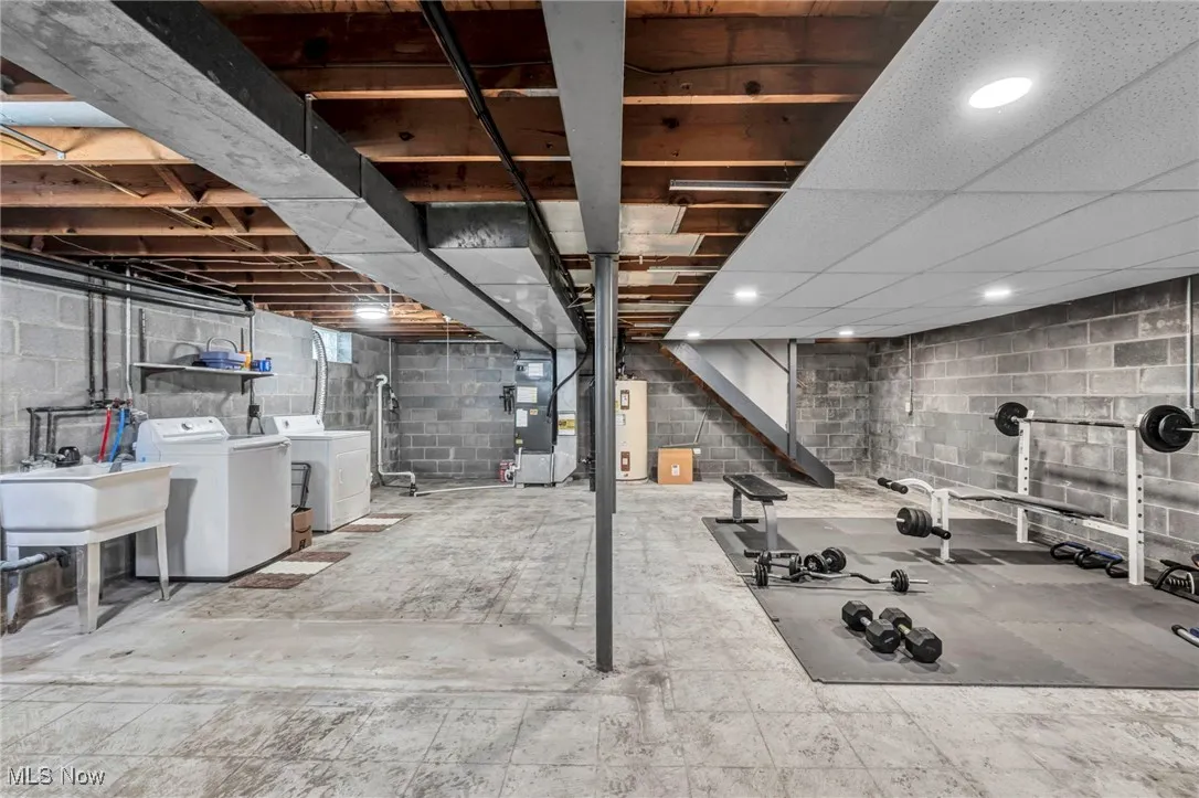 Unfinished basement featuring heating unit, separate washer and dryer, and water heater