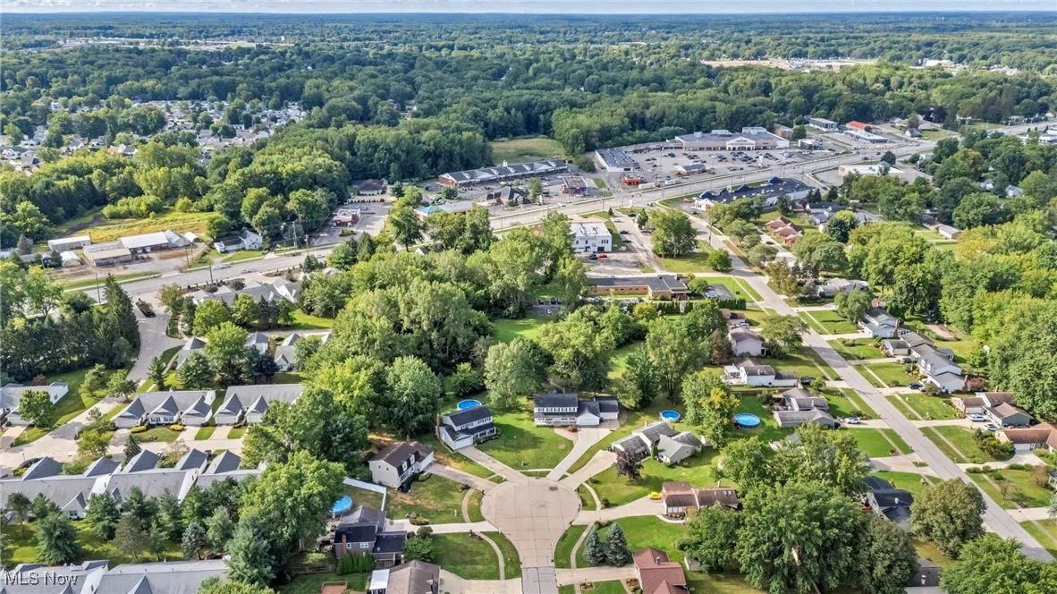 Aerial overview of property's location with nearby suburban area and a tree filled landscape