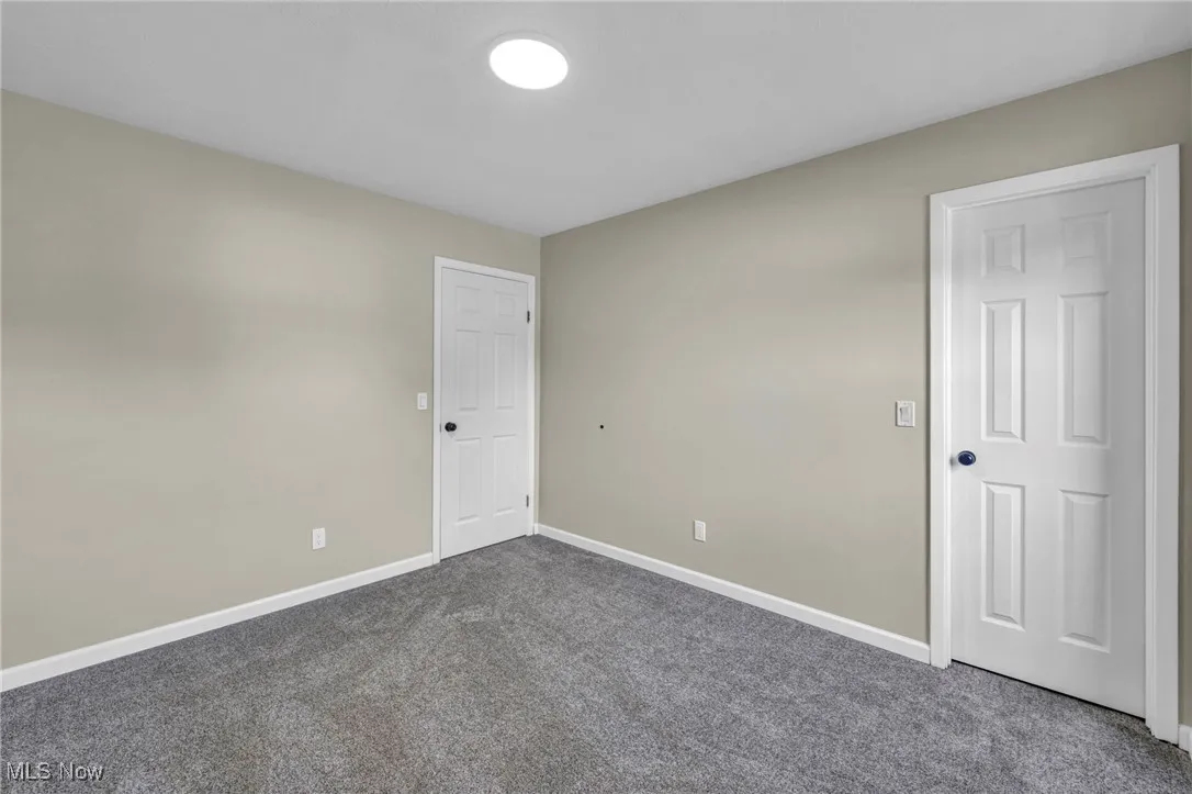 Empty room featuring dark carpet and baseboards