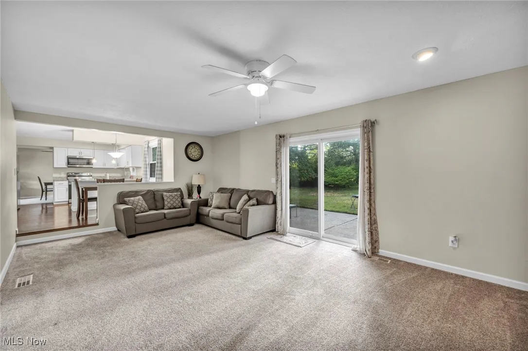 Carpeted living room with ceiling fan and baseboards
