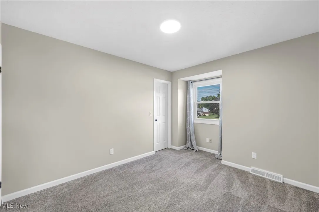 Unfurnished room featuring light colored carpet and baseboards
