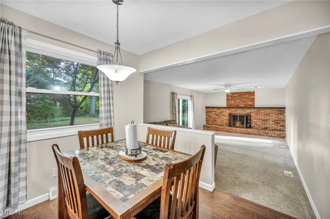 Dining room featuring dark wood-style floors, a brick fireplace, and dark carpet