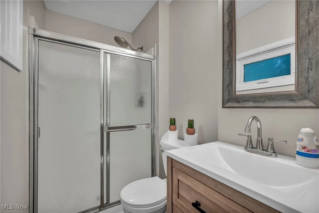 Bathroom featuring vanity, a shower stall, and a textured ceiling