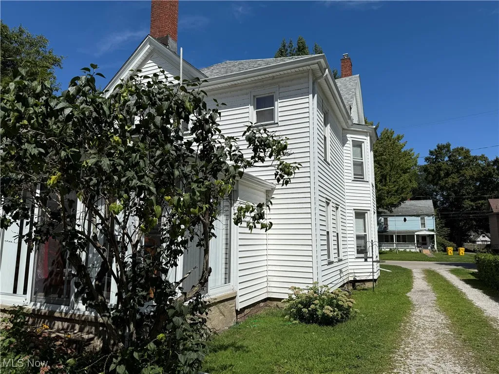 View of side of home with a chimney and a lawn