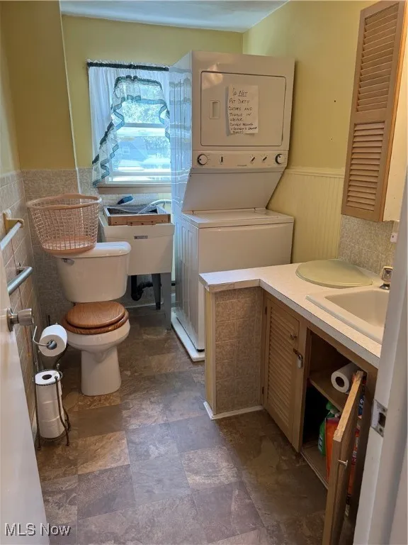 Bathroom featuring a wainscoted wall, estacked washer and dryer, and vanity