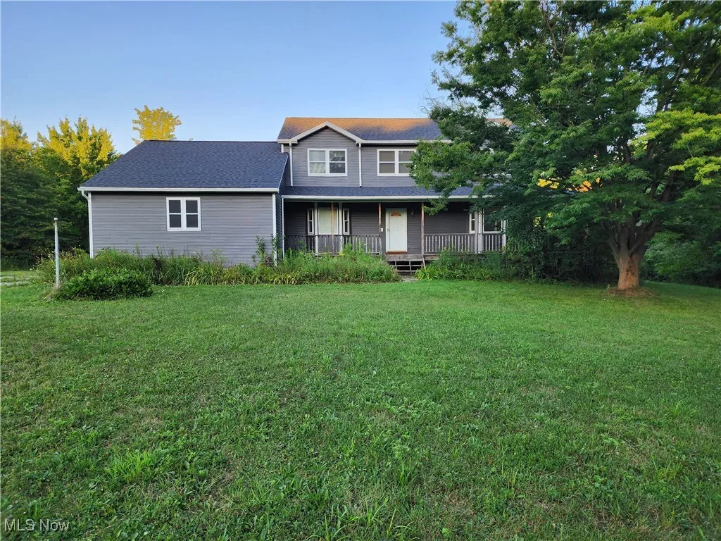 Traditional-style house featuring covered porch and a front yard
