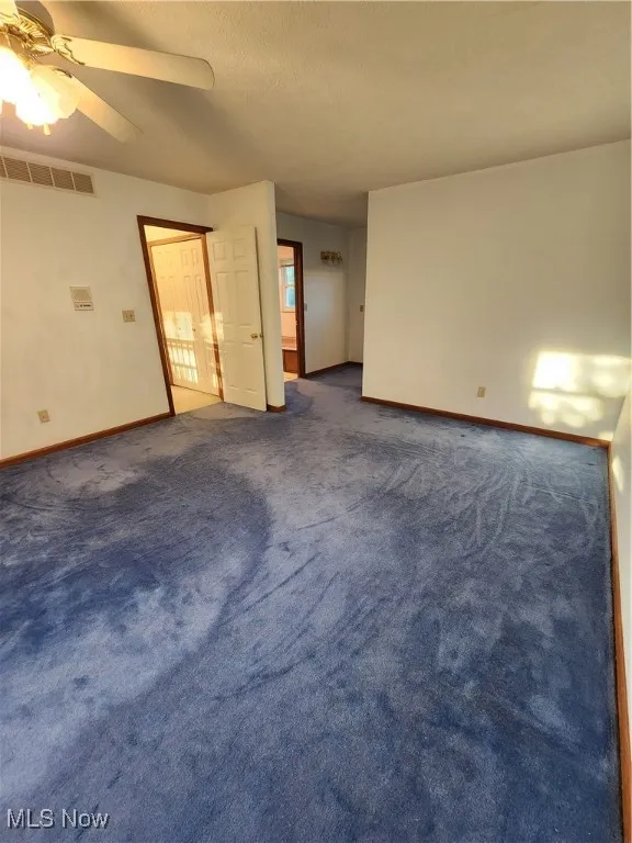 Carpeted room with ceiling fan and a textured ceiling