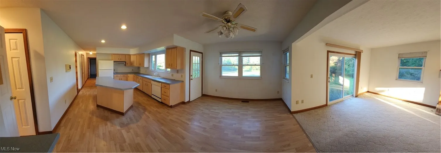 Kitchen with light cabinets, a ceiling fan, light Pergo wood finished floors, dishwasher, and a center island