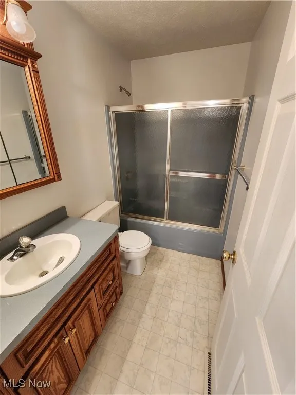 2nd floor Full bath featuring combined bath / shower with glass door, vanity, and a textured ceiling