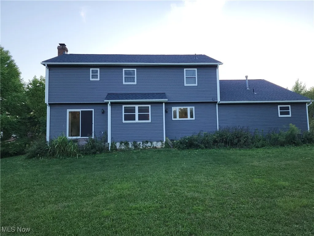 Back of property with a yard and a chimney