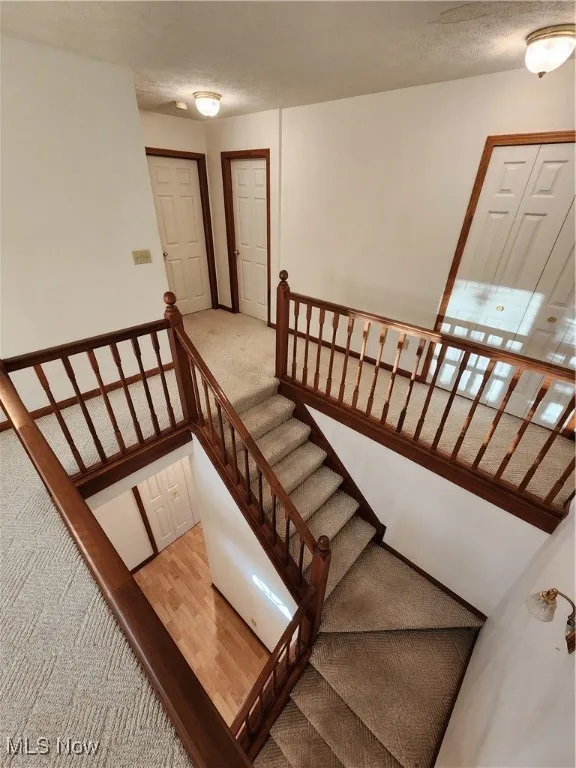 Stairs featuring carpet, a textured ceiling, and Pergo wood finished floors