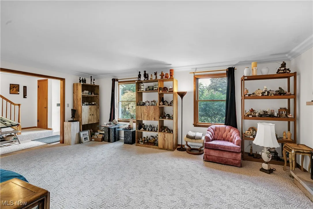 Sitting room featuring ornamental molding, carpet flooring, healthy amount of natural light, and stairway