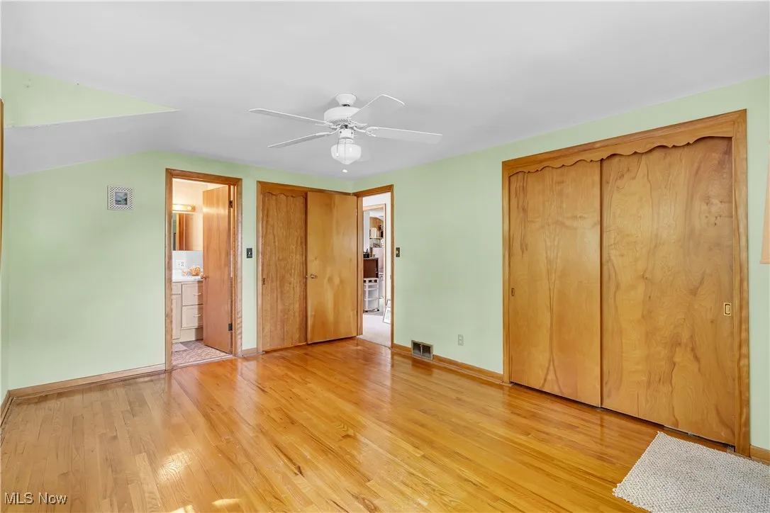 Unfurnished bedroom with light wood-style floors, a closet, ceiling fan, and ensuite bathroom