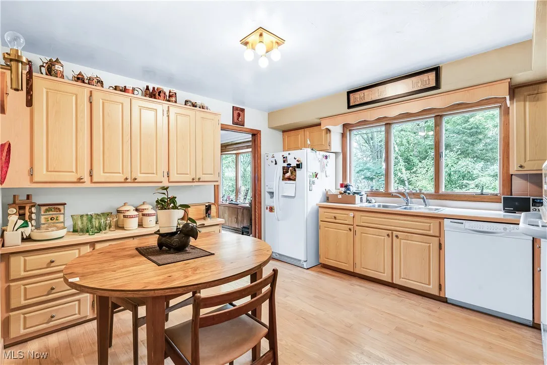 Kitchen with white appliances, light wood-style floors, light countertops, and light brown cabinets