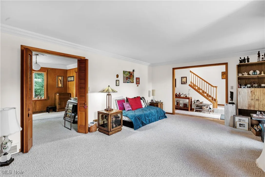 Carpeted living room featuring crown molding and stairway