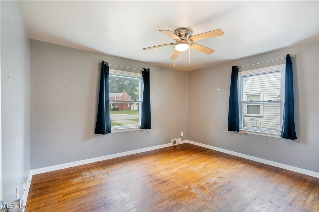 Empty room with light wood-style floors, healthy amount of natural light, and ceiling fan