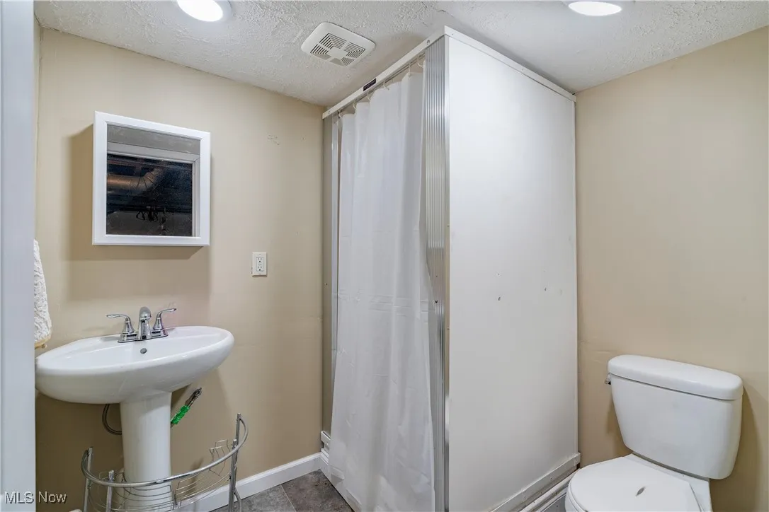Full bathroom featuring a textured ceiling and a shower with shower curtain