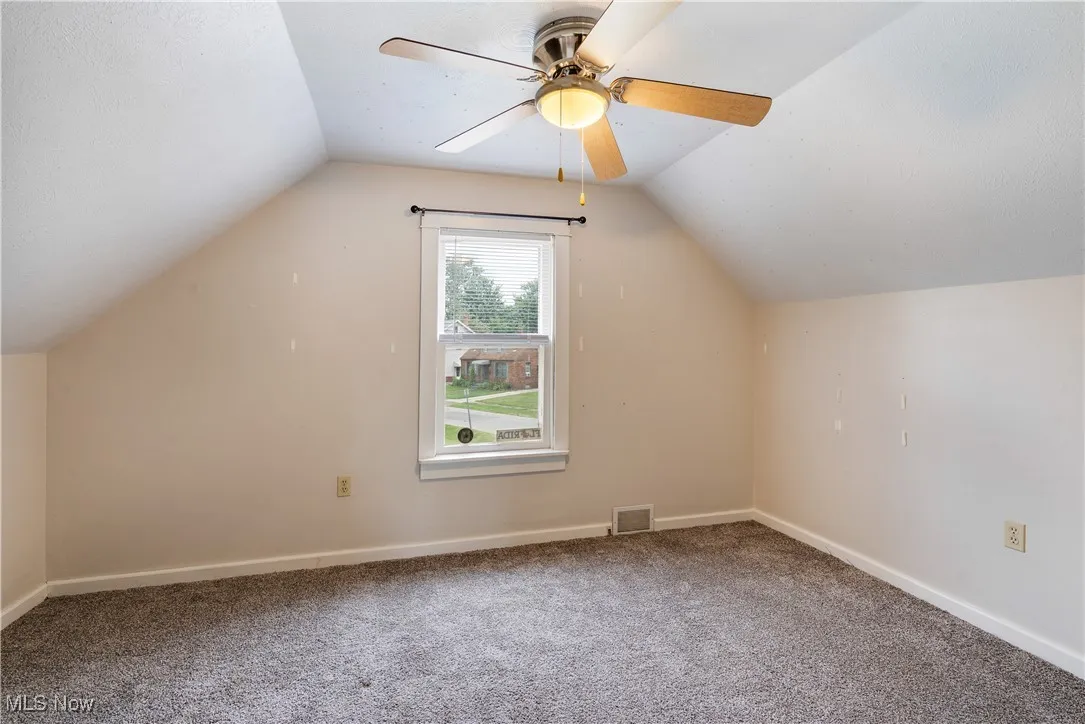 Bonus room with lofted ceiling, carpet floors, and a ceiling fan
