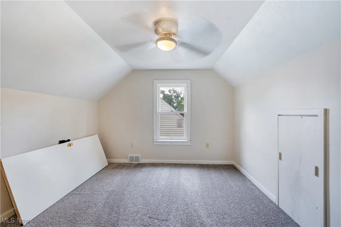 Additional living space with vaulted ceiling, carpet, and ceiling fan