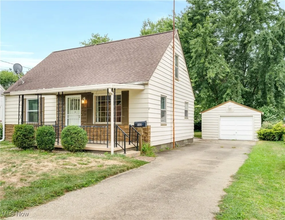 View of front of property with roof with shingles, a porch, an outbuilding, a garage, and driveway
