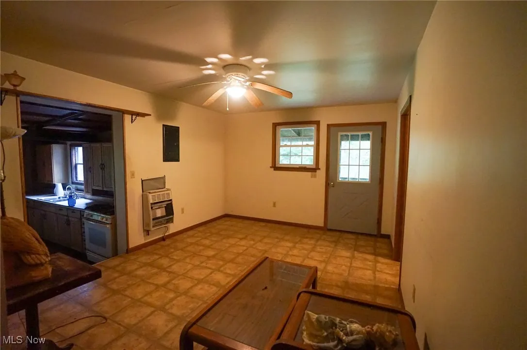 Unfurnished living room featuring a ceiling fan and heating unit