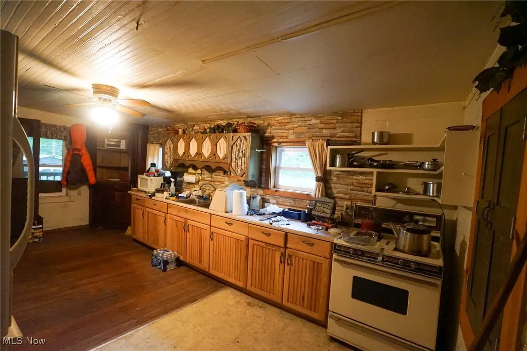 Kitchen featuring white appliances, light countertops, open shelves, dark wood finished floors, and a ceiling fan