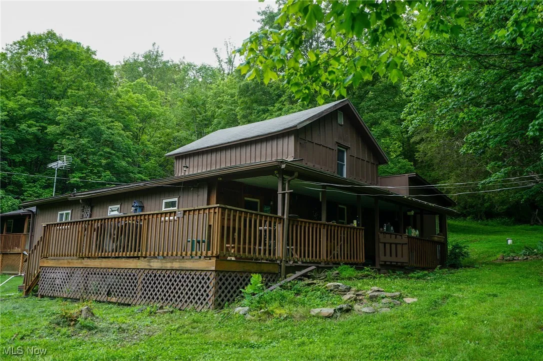 Rear view of house with a lawn, covered porch, and a view of trees