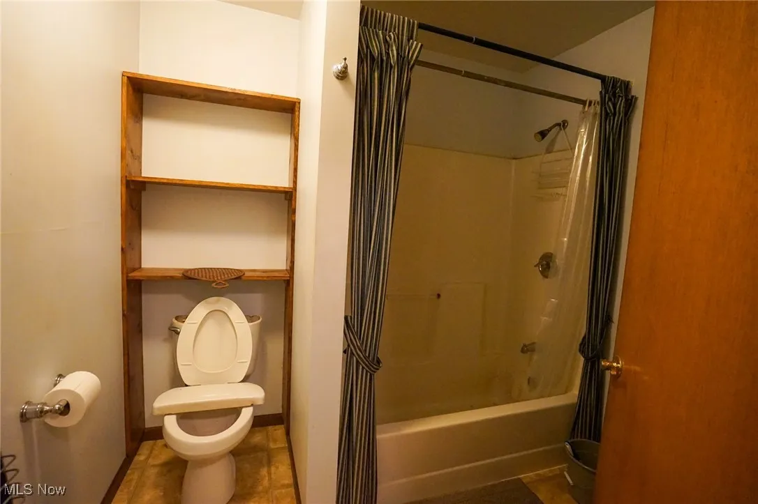 Full bathroom with shower / tub combo with curtain and tile patterned floors