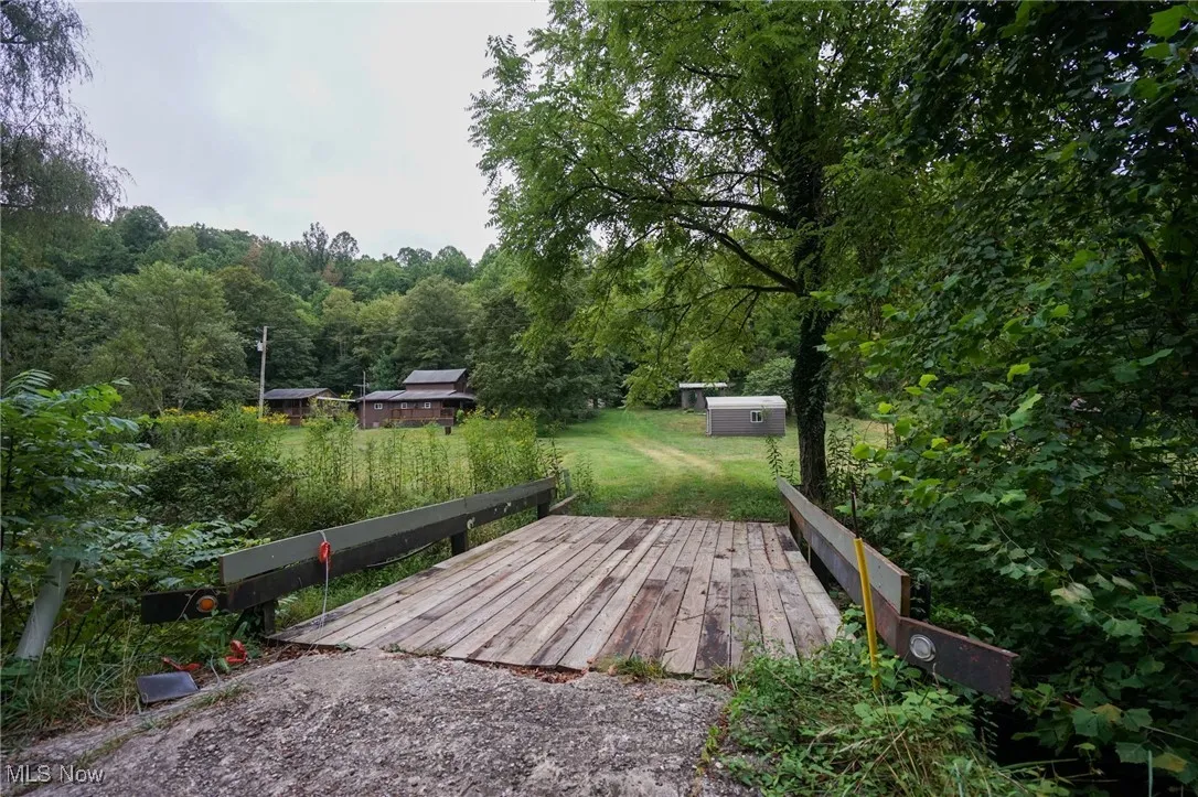 Wooden terrace with a shed, a lawn, and a forest view