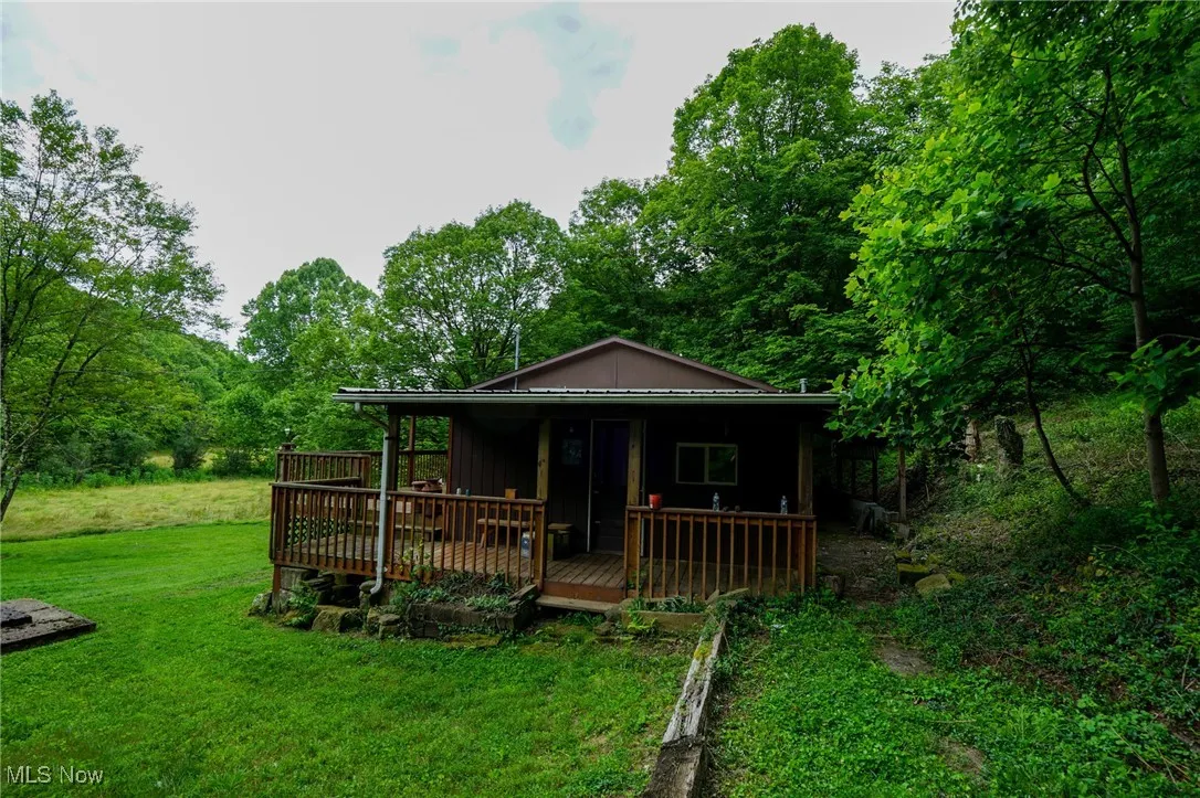 Back of house featuring a lawn, view of wooded area, board and batten siding, and a wooden deck
