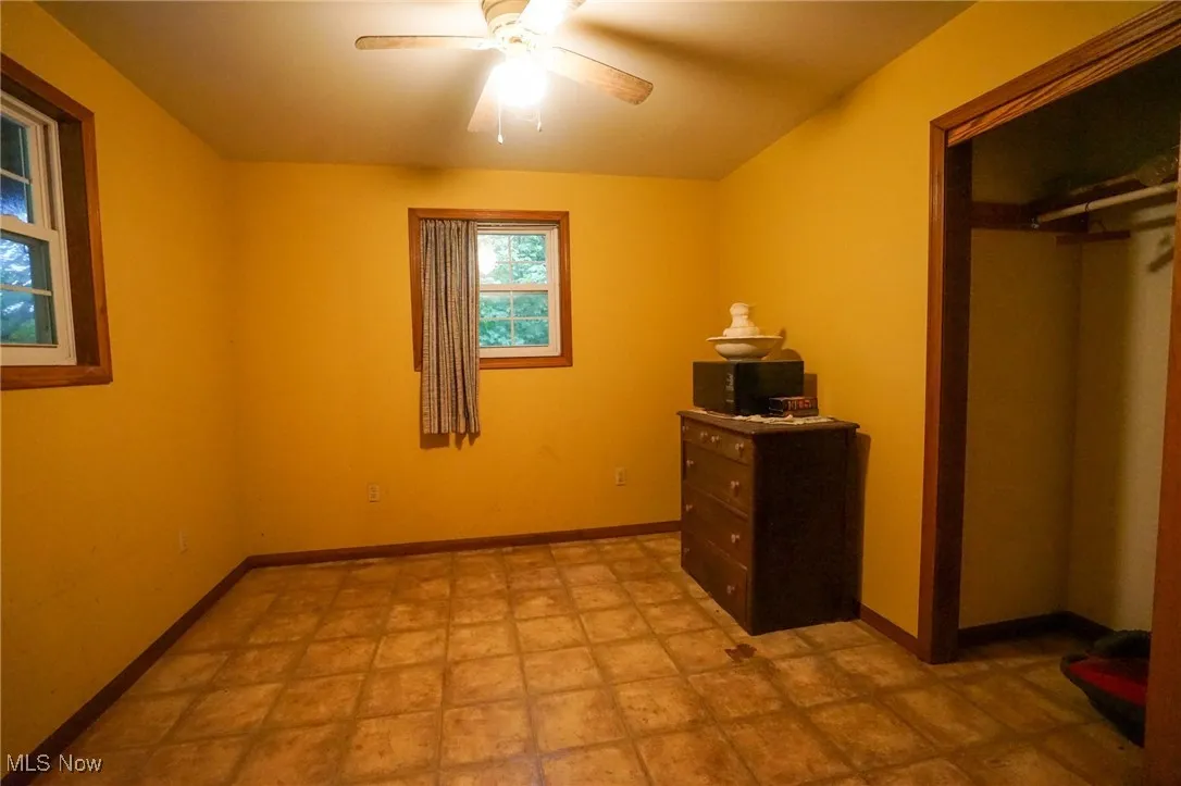 Unfurnished bedroom with ceiling fan and a closet