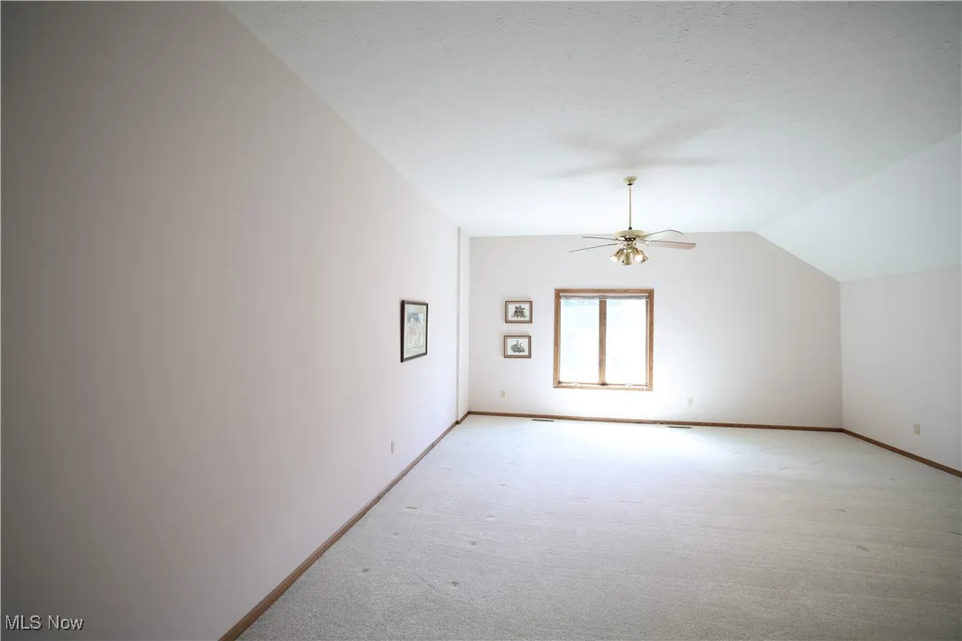 Second floor bonus room featuring vaulted ceiling, carpet floors, and ceiling fan