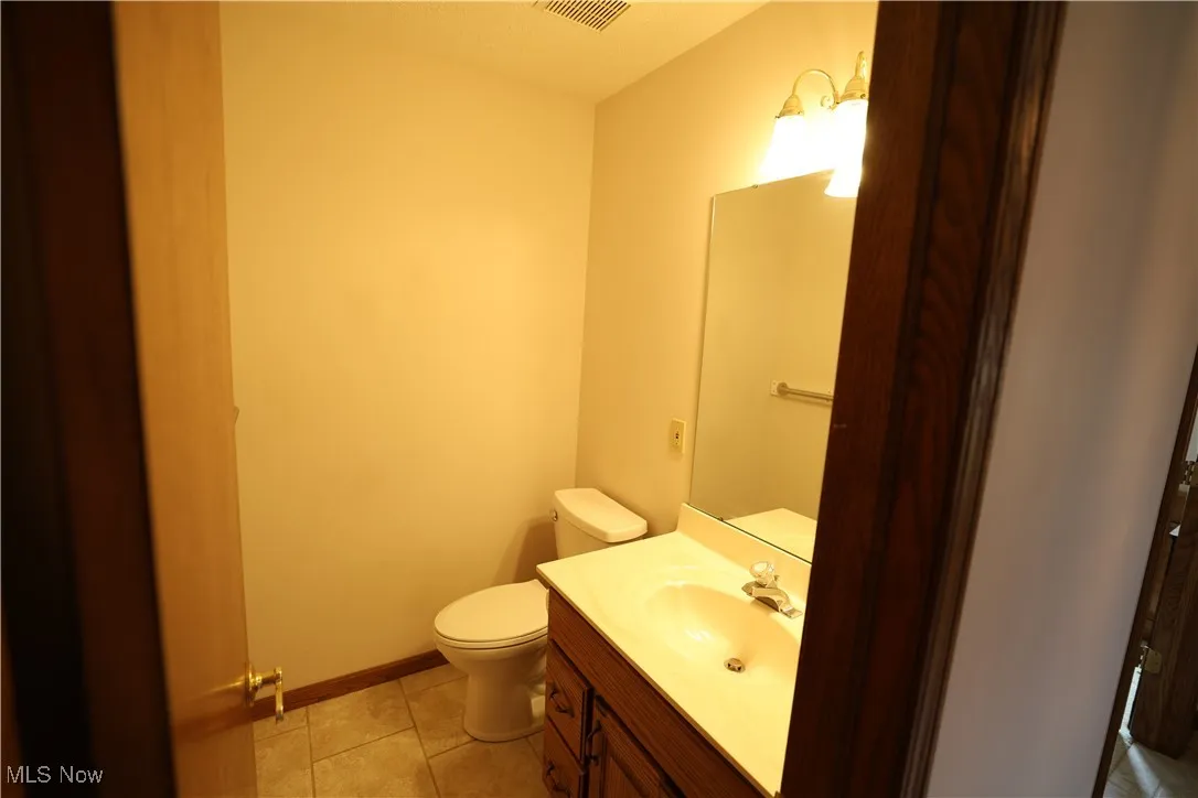 1st floor half bathroom with light tile flooring and vanity