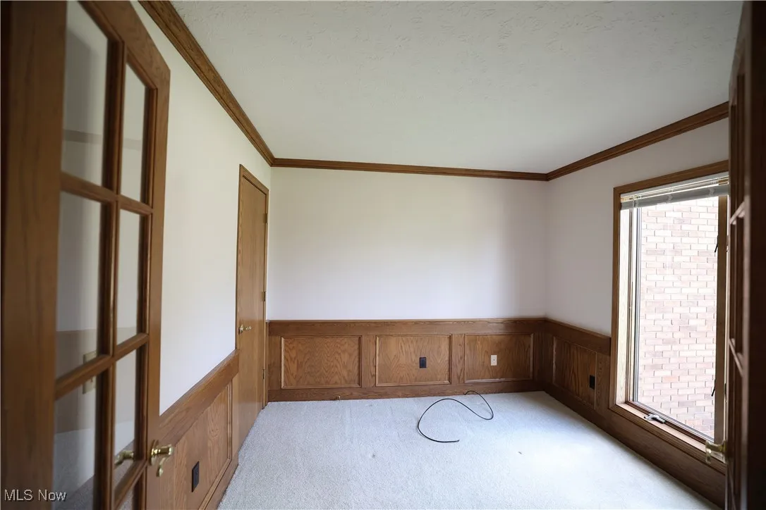 Office/den featuring light carpet, wainscoting, crown molding, french doors, and a textured ceiling
