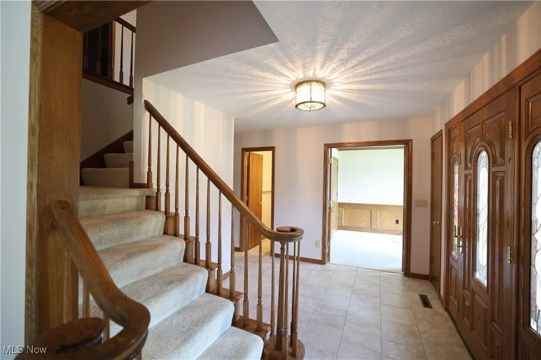 Entrance foyer featuring stairway, a textured ceiling, and light tile patterned floors