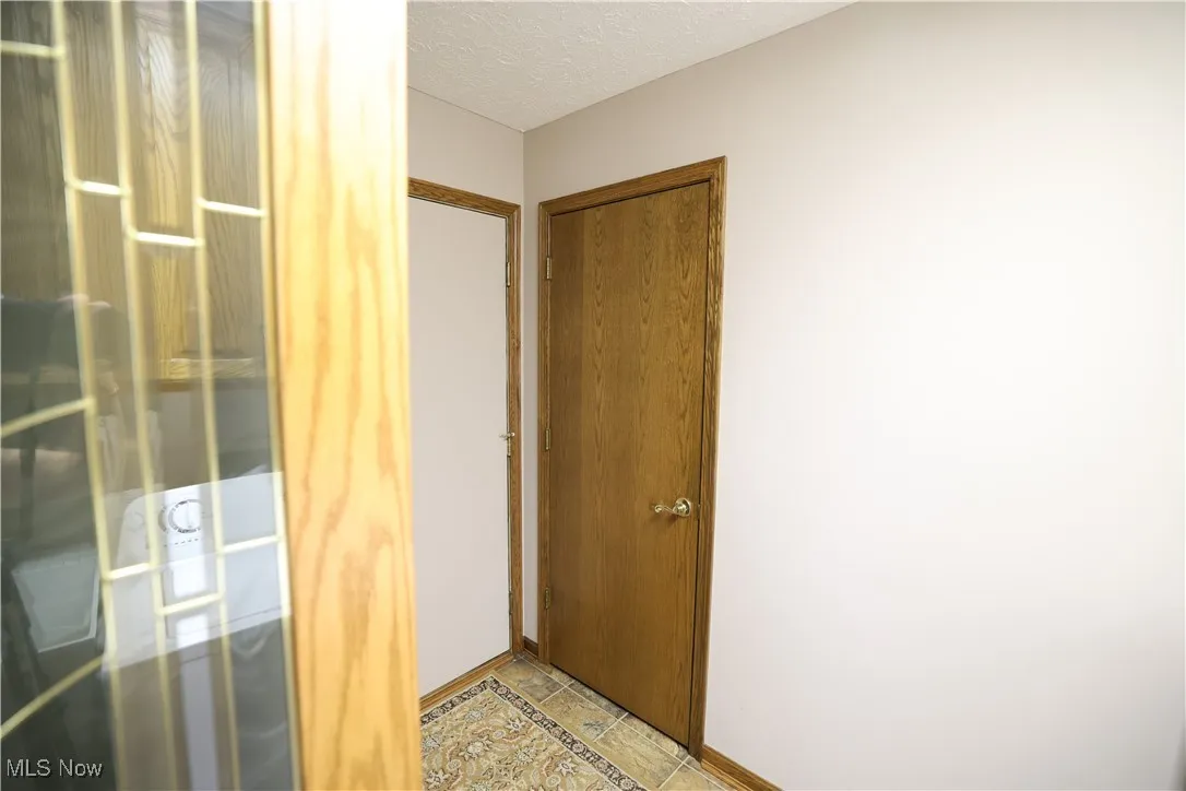 Doorway in laundry room to 3-car attached garage and a textured ceiling and vinyl patterned flooring