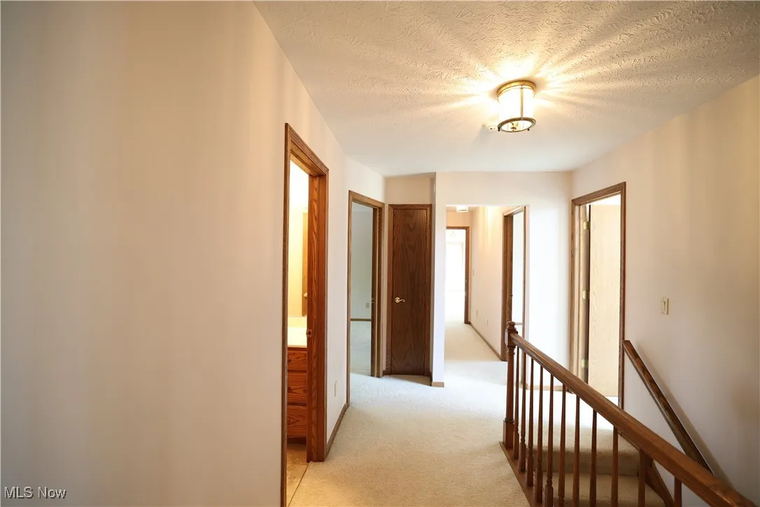 Second floor hallway with a textured ceiling, light carpet, and an upstairs landing