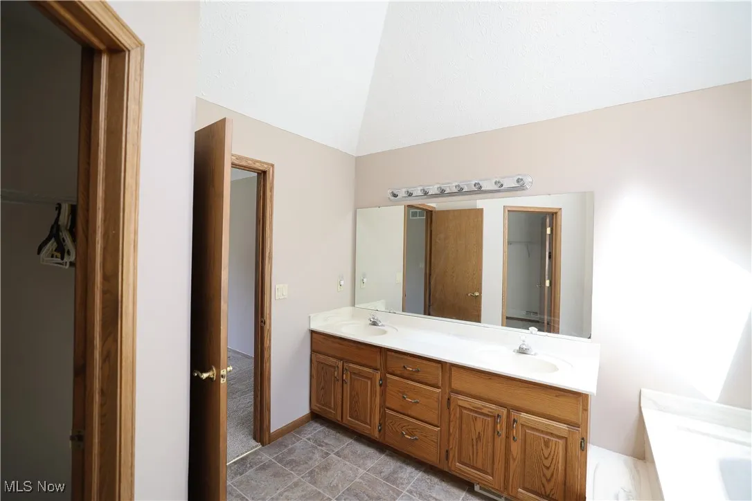 Primary bathroom featuring double vanity, and vaulted ceilings