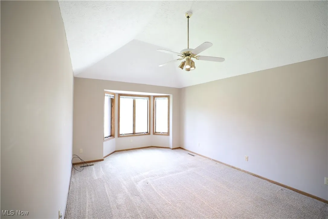 Primary bedroom featuring vaulted ceiling, and a large bay window