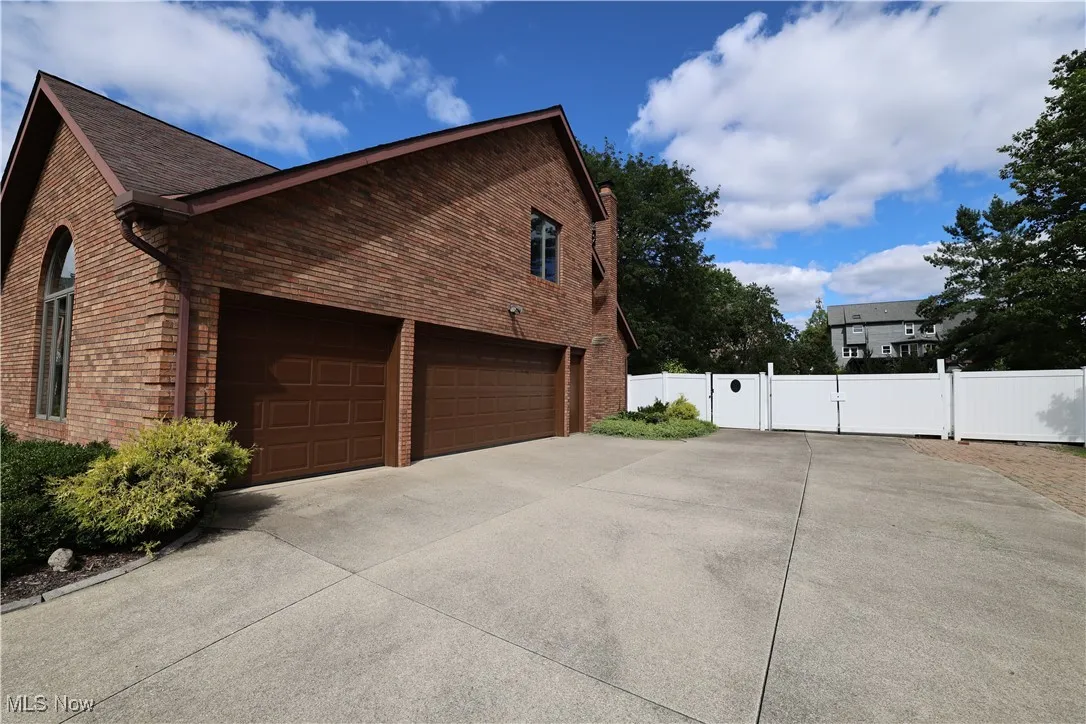 View of home's exterior with a gate, brick siding, a 3-car garage, and driveway