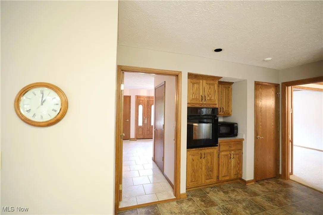 Kitchen featuring built in oven, microwave, oak cabinetry, recessed lighting and a textured ceiling