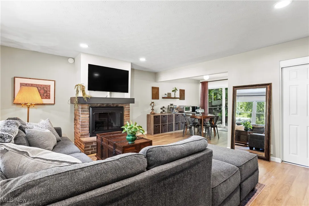 Living room featuring light wood finished floors, a fireplace, and recessed lighting