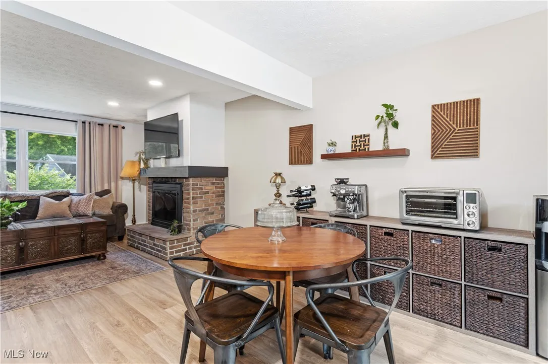 Dining room featuring light wood finished floors, a fireplace, recessed lighting, and a textured ceiling
